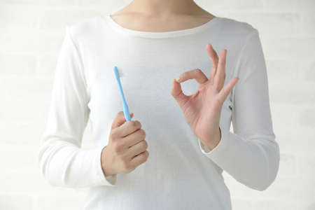 Dental Care Image - A Woman Who Brings a Toothbrush and Issues Ok Sign