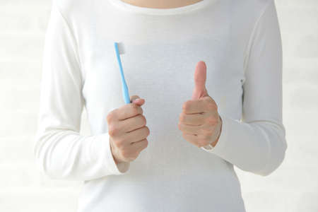 Dental Care Image: A Woman Raising her Thumbs Up with a Toothbrush