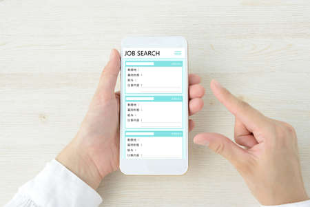 The hand of someone looking for a job on their smartphone