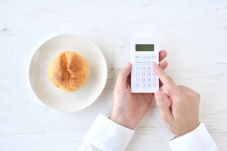 Diet image - the hand of the person who calculates the calories of cream puffs