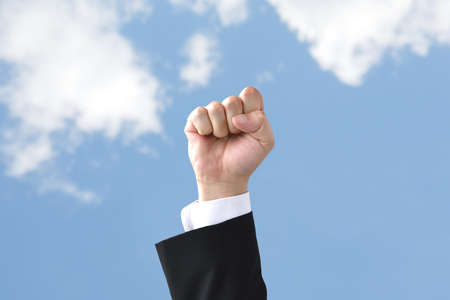 Businessman's hand thrust up into the blue skyの写真素材