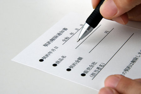 In the hands of the person filling out the contract cancellation noticeの写真素材