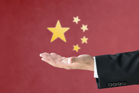 A man's hand holding a star on the Chinese flagの写真素材