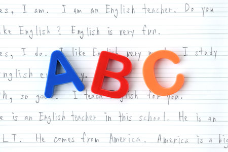 Alphabet block placed on top of English notebookの写真素材
