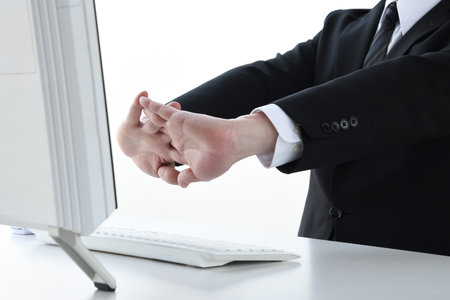 Businesswoman stretching while working at deskの写真素材