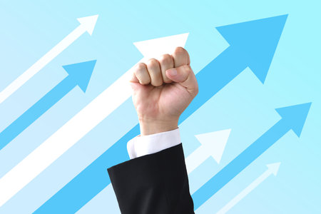 A businessman's fist with an arrow going up to the rightの写真素材