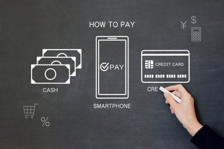 A man's hand drawing icons of various payment methods on a blackboardの写真素材