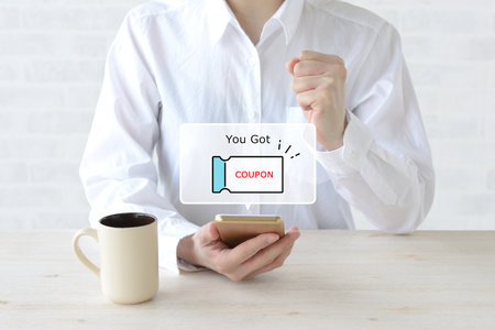 Image of a woman happy to receive a coupon on her smartphoneの写真素材