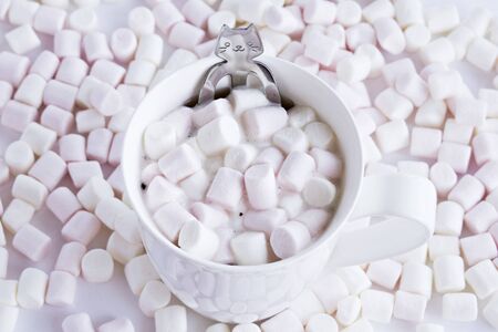 Tea cup with pink and white marshmallows and funny cat spoonの写真素材