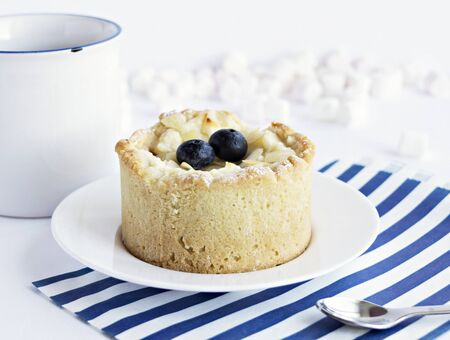 Cake with blueberry, tea cup, marshmallows and blue striped paper bag on the tableの写真素材