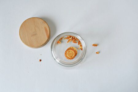 Glass jar with wooden cover and cookie leftovers over whiteの写真素材