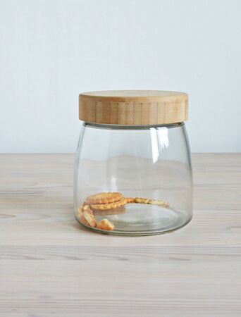 Glass jar with cookie leftovers and crumbs on the wooden tableの写真素材