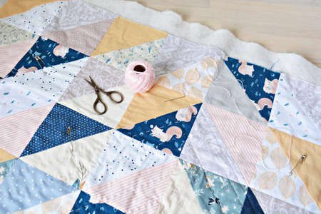 Hand stitch quilting process: cotton thread, needle and scissors on the tableの写真素材