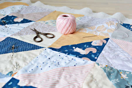 Hand stitch quilting process: cotton thread, needle and scissors on the tableの写真素材