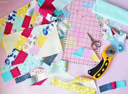 Creative mess: fabric scraps, scissors, rotary cutter, seam ripper, quilting ruler and cutting mat