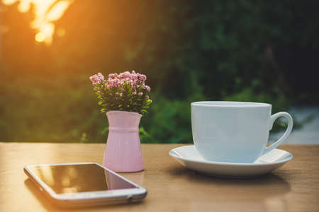 The mobile , a vase of flowers and a cup of coffeeの写真素材