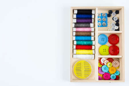 The sewing kit in the Wooden tray is placed on  white