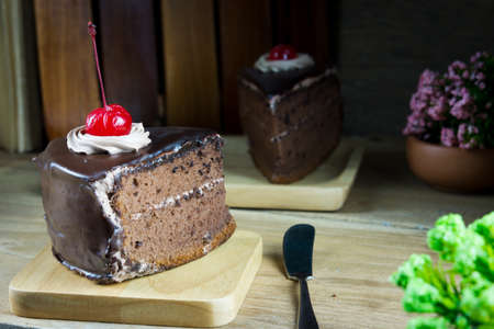 Delicious chocolate cake in wooden plate on wooden table background, closeup, life style.の写真素材