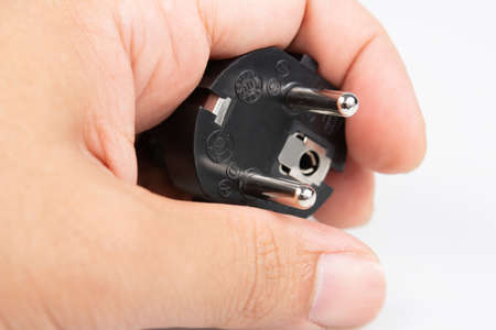 Close up of male hand holding electric plug