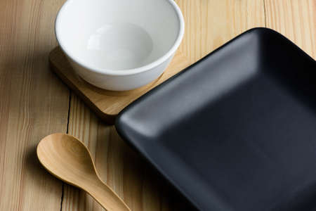 Empty black plate and white bowl on the wooden table