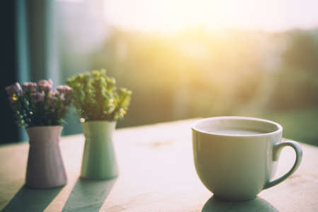 flowers in a vase and cup of coffee on the rustic style backgroundの写真素材