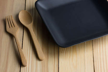 Empty ceramic black plate on the wooden tableの写真素材