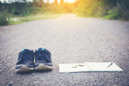 Old shoes pocket watch and notebook on the road, vintage style.