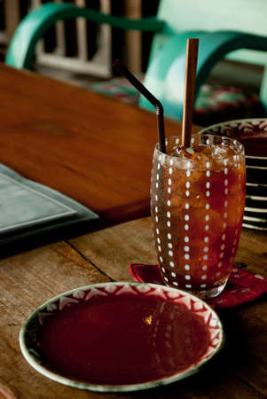 Lemon ice tea and empty red dish on the wood tableの写真素材