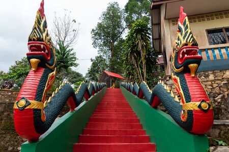 Red and green ladder with two naga statue in  Had Som Pan temple, Ranong, Thailand.の写真素材
