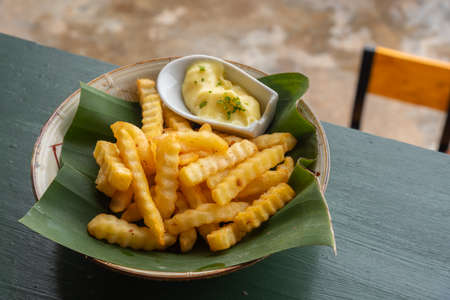 Tasty french fries on banana leaf and ceramic bowl with mayo sauce.の写真素材