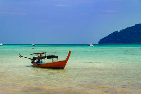 Thailand nature landscape. A long tail boat by the beach in Thailand green mountains and blue skyの写真素材