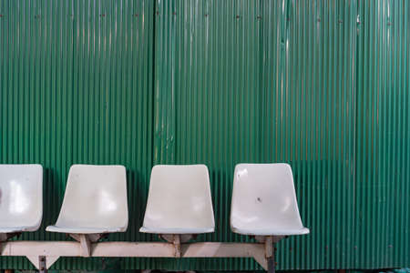 White plastic seats at temporary bus stop with zinc wall background.の写真素材