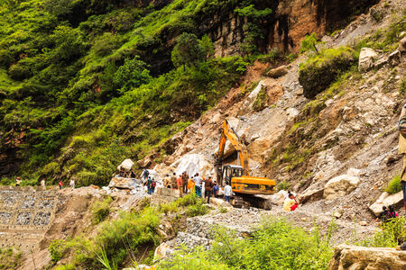 India - August 9 : The officers try to clear the big rock on highway from rishikech to joshimath after landslide due to heavy rain on August 9, 2014 in Indiaのeditorial素材