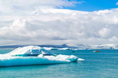 Iceberg and sightseeing boats in Jokulsarlon, a glacial river lagoon in southeast Icelandの写真素材
