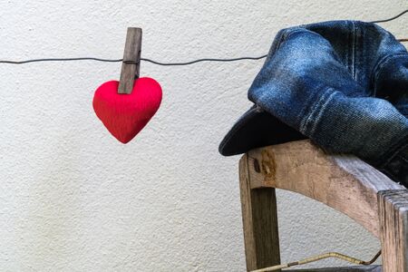 Red heart hanging on a wire against a white wallの写真素材