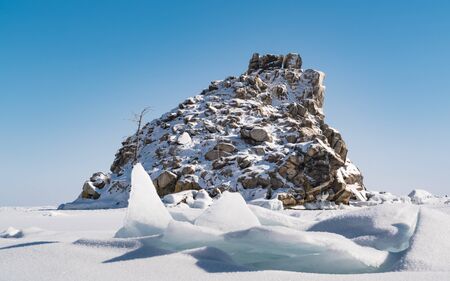 Small rocky island cover with snow in Frozen Lake Baikal, Russiaの写真素材