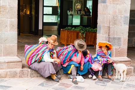 CUSCO, PERU - JANUARY 26, 2016 : Unidentified Peruvian people wearing colorful traditional clothing  and hat with their animal sitting in front of a shop in cusco to take a restのeditorial素材