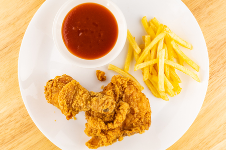 Crispy fried chicken with a pile of fried potatoes and a cup of ketchup on white plateの写真素材