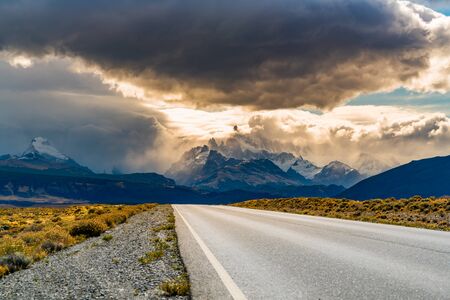 View of the road to El Chalten with Mount Fitz Roy in the mist and  rain clouds in the sky at...