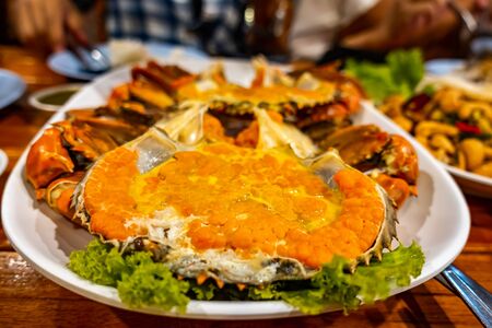 Steamed egg crab with claws and vegetable in white dish on a wooden table.の写真素材