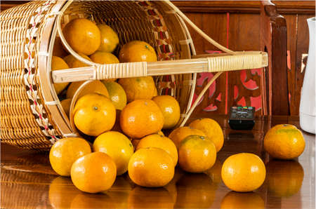 View of oranges in a bamboo basket on wooden table.の写真素材