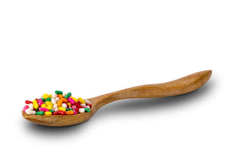 Side view of rainbow sprinkles in wooden spoon on white background