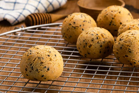 Freshly baked homemade mochi bun on metal cooling rack with honey dipper, dish cloth, wooden cup on...
