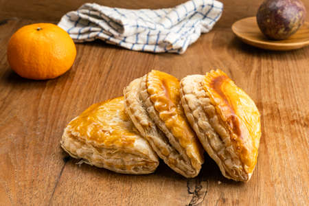 Delicious homemade tuna pie on wooden table with passion fruit in wooden plate, ripe orange and...