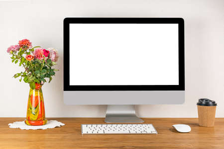 Blank screen desktop computer with wireless keyboard and mouse on wooden table in a working room...