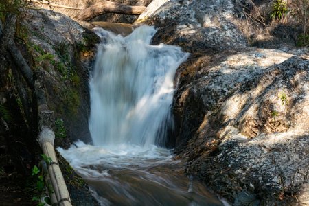 Natural clear mountain stream water flowing down over boulders in the shade of trees at Chae Son National Park in Thailand.の写真素材