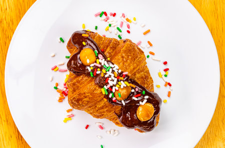 Croissant garnished with chocolate and rainbow sprinkles. Top view of delicious french croissant...