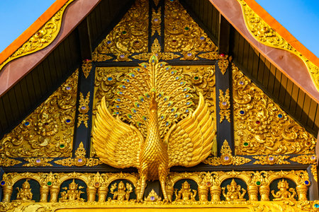 Sculpture of golden Peacock at the facade of main hall in a buddhist temple, Wat Phra That Doi Phra Chan in Lampang Province, Thailand.の写真素材