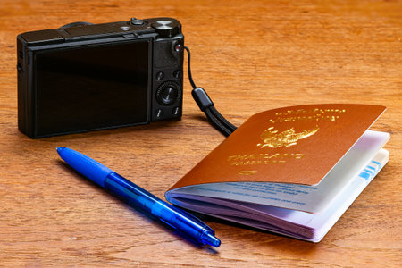 View of Thai passport, blue ballpoint pen and digital compact camera on wooden table.の写真素材