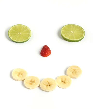 happy smiley face made from sliced banana strawberry lime fruit isolated on white backgroundの写真素材
